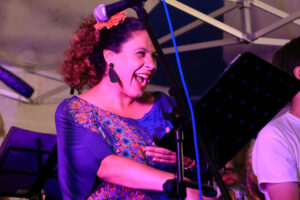 Karla, singer from Ran Kan Kan, in a blue dress, with a joyful face.