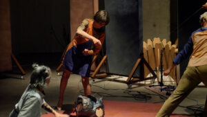 An artist holds a string attached to a black ceramic sculpture on the floor - the photo captures a moment in Rita Evans' Tuning in a Vacuum piece