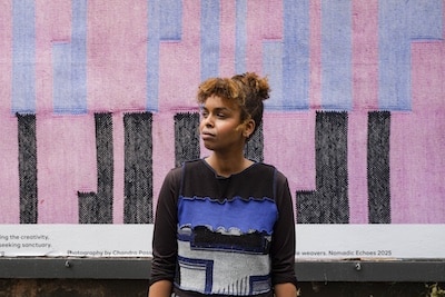 Portrait of Ayan Cilmi in front of textile artwork